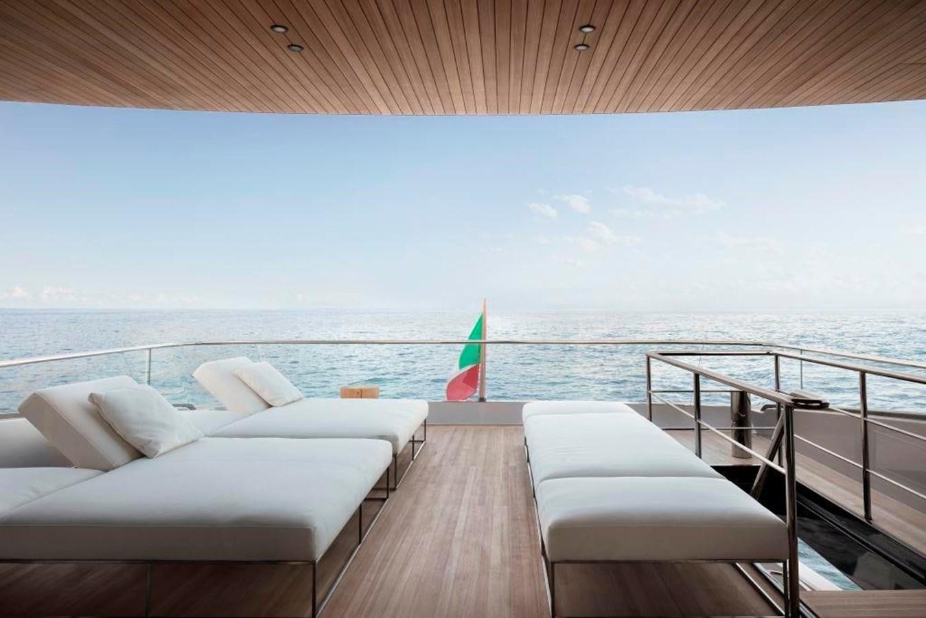 a deck with a beach and a umbrella aboard HM 1 Yacht for Sale