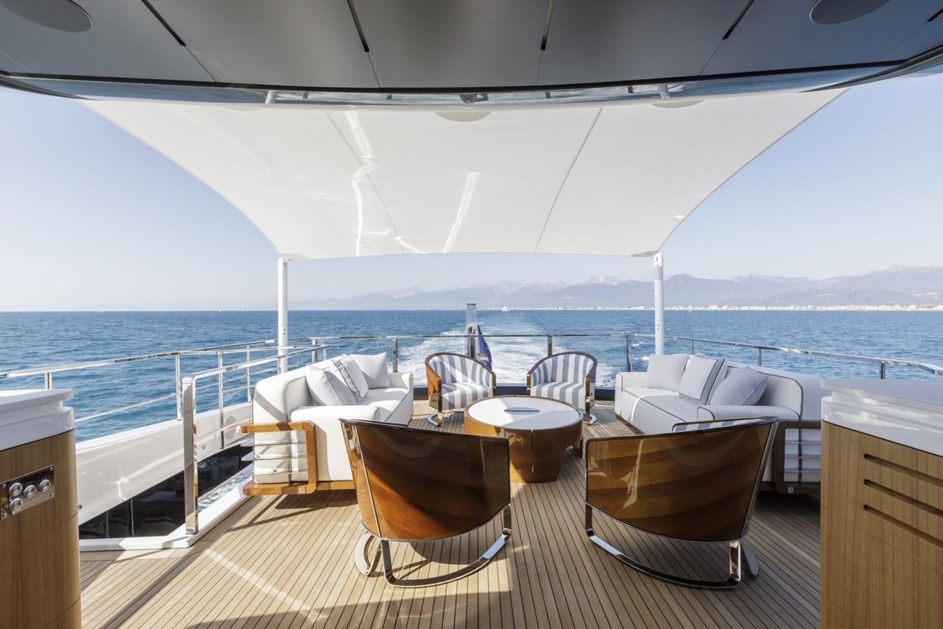 a table and chairs on a deck overlooking a body of water aboard MYSTERE Yacht for Sale