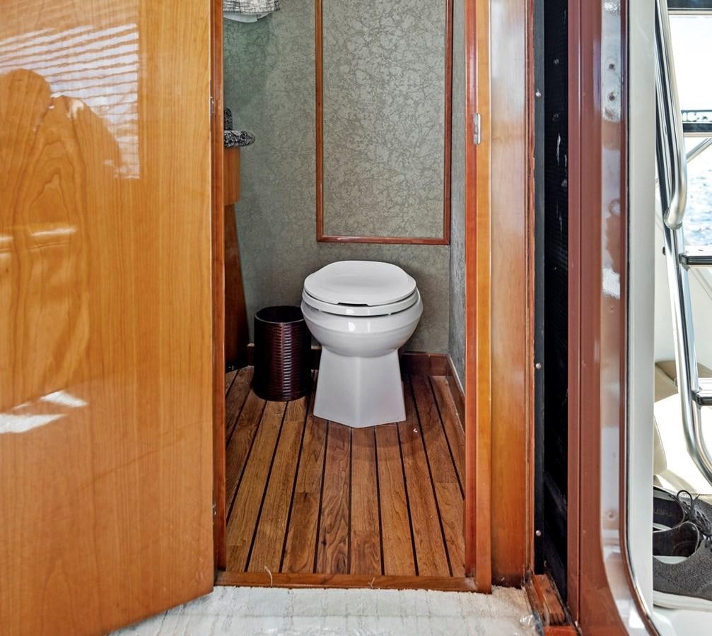 a small bathroom with a wood door aboard NAUTICAL NOMAD Yacht for Sale