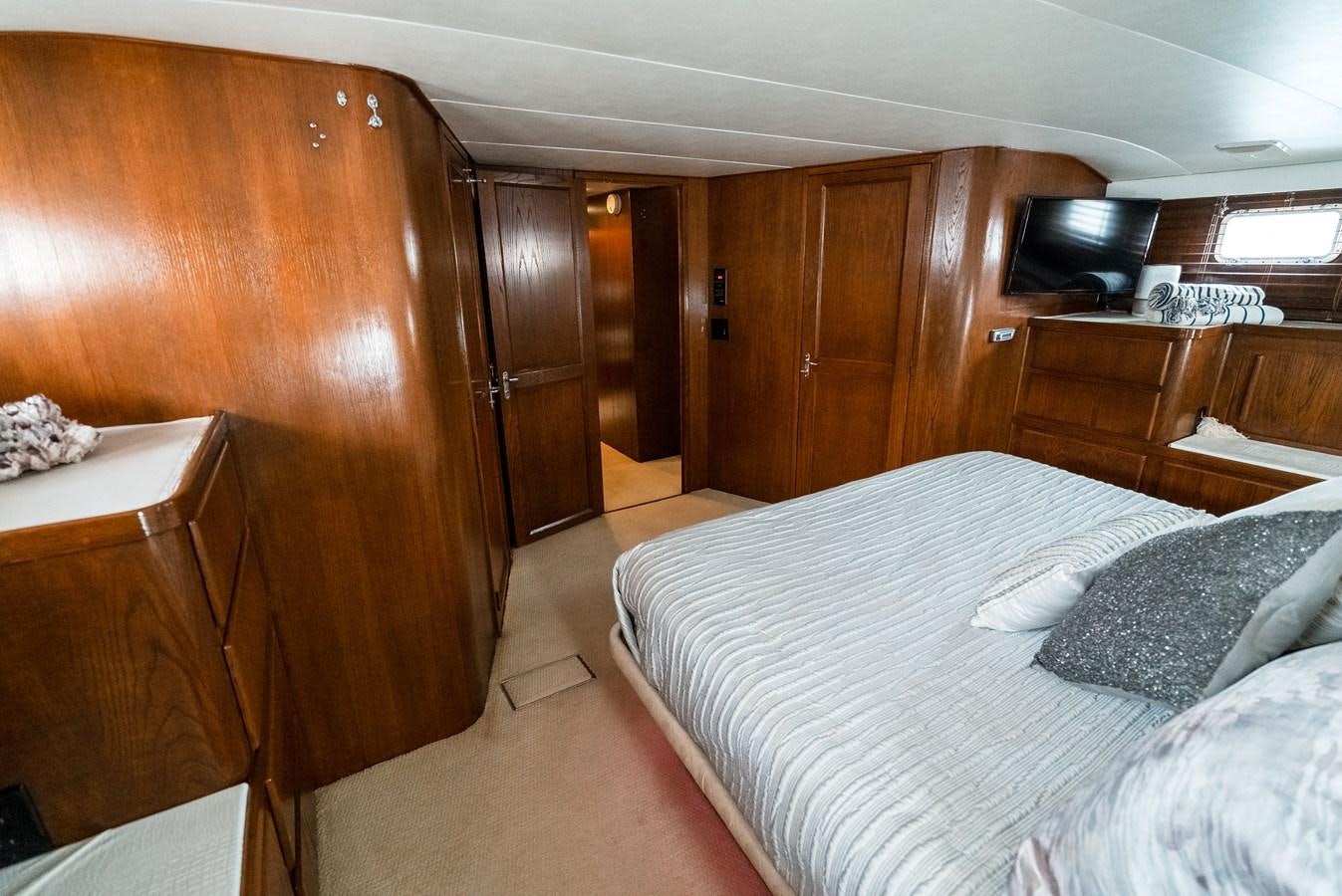 a bedroom with a bed and a wood cabinet aboard HIGH IMPACT Yacht for Sale