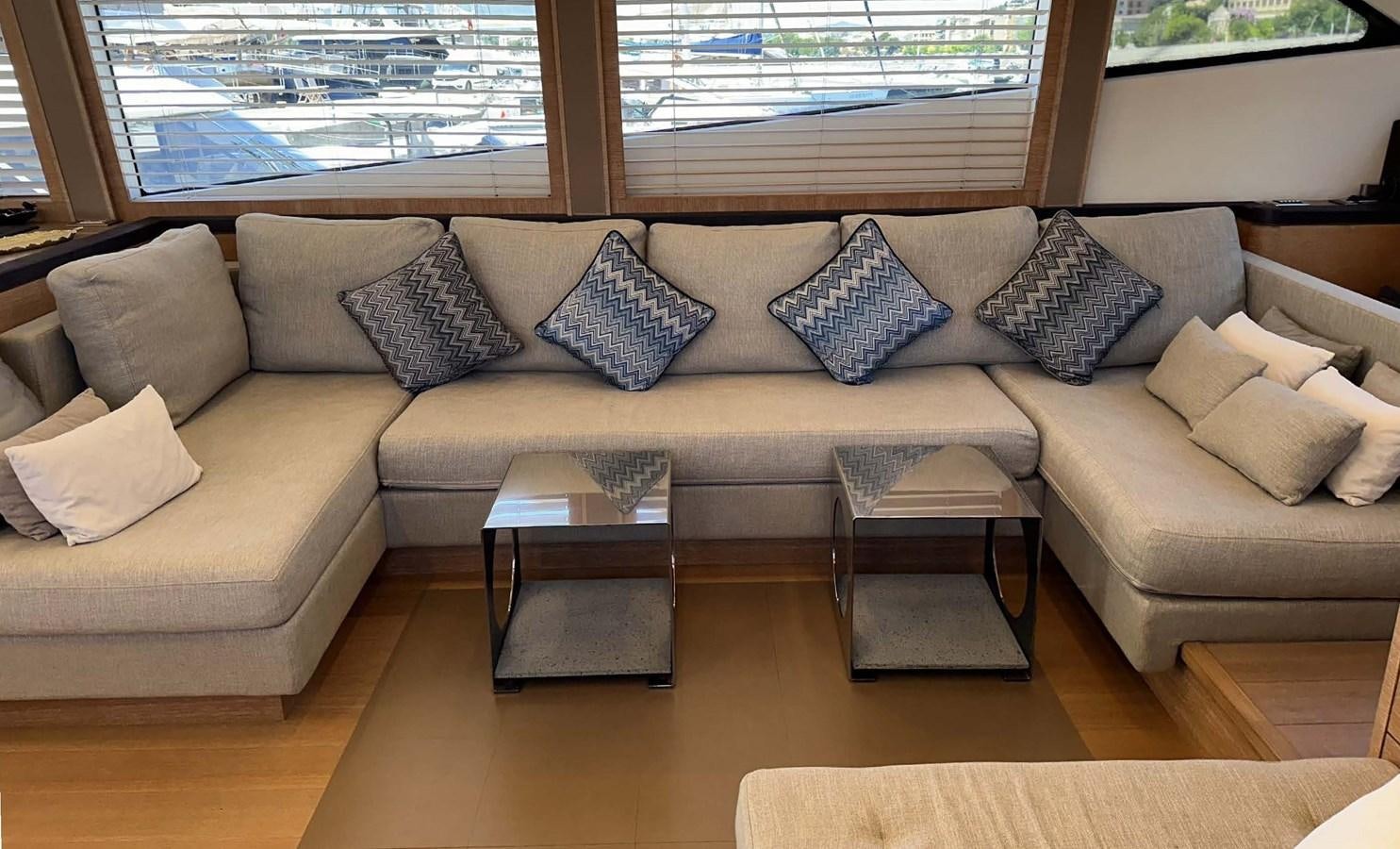 a couch with pillows and a coffee table in front of a window aboard TYCHE Yacht for Sale