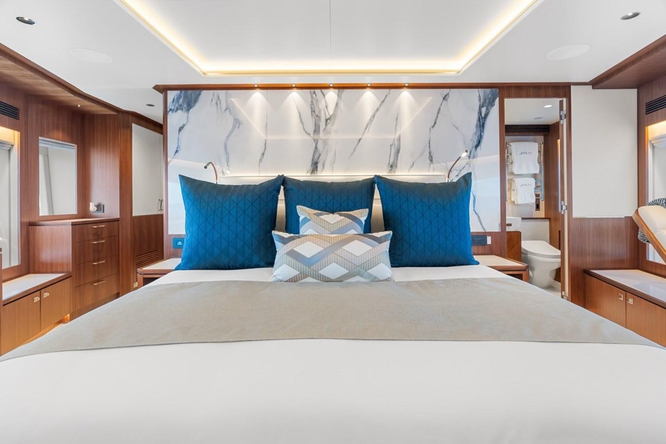 a bed with blue pillows aboard JEMILY II Yacht for Sale