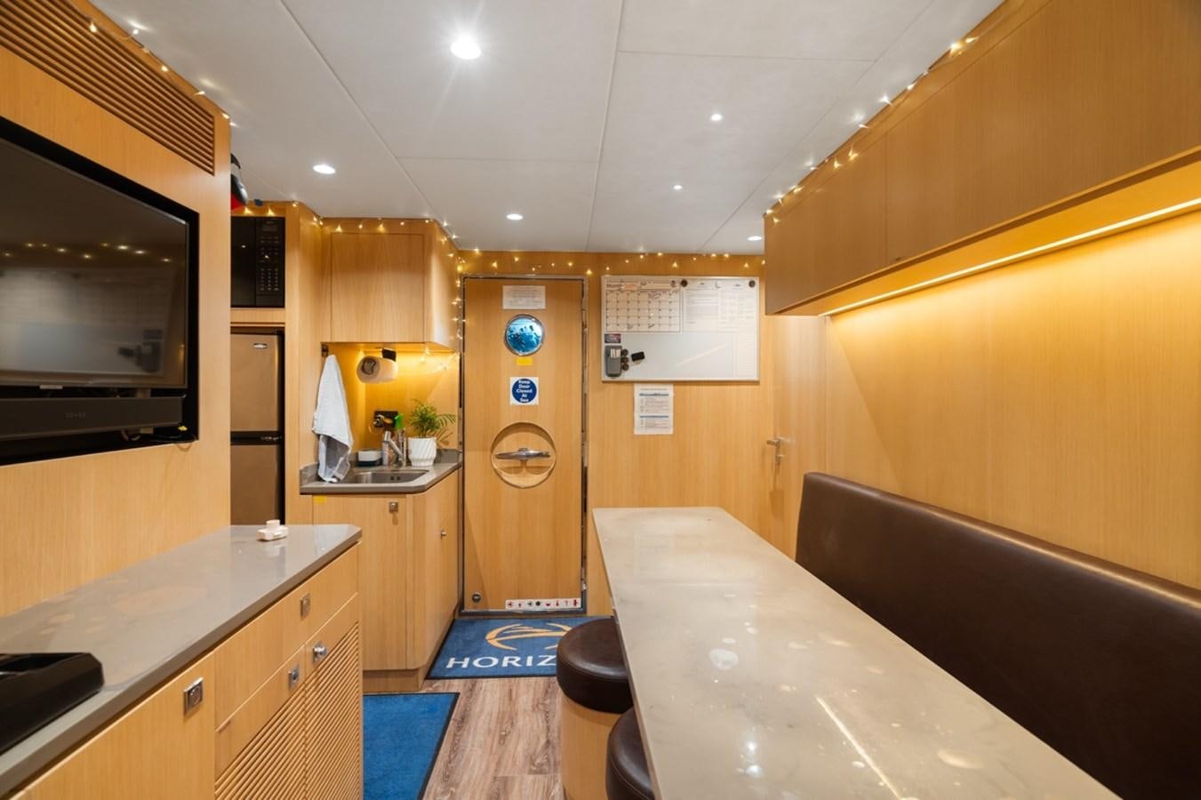 a kitchen with a table and a tv aboard JEMILY II Yacht for Sale