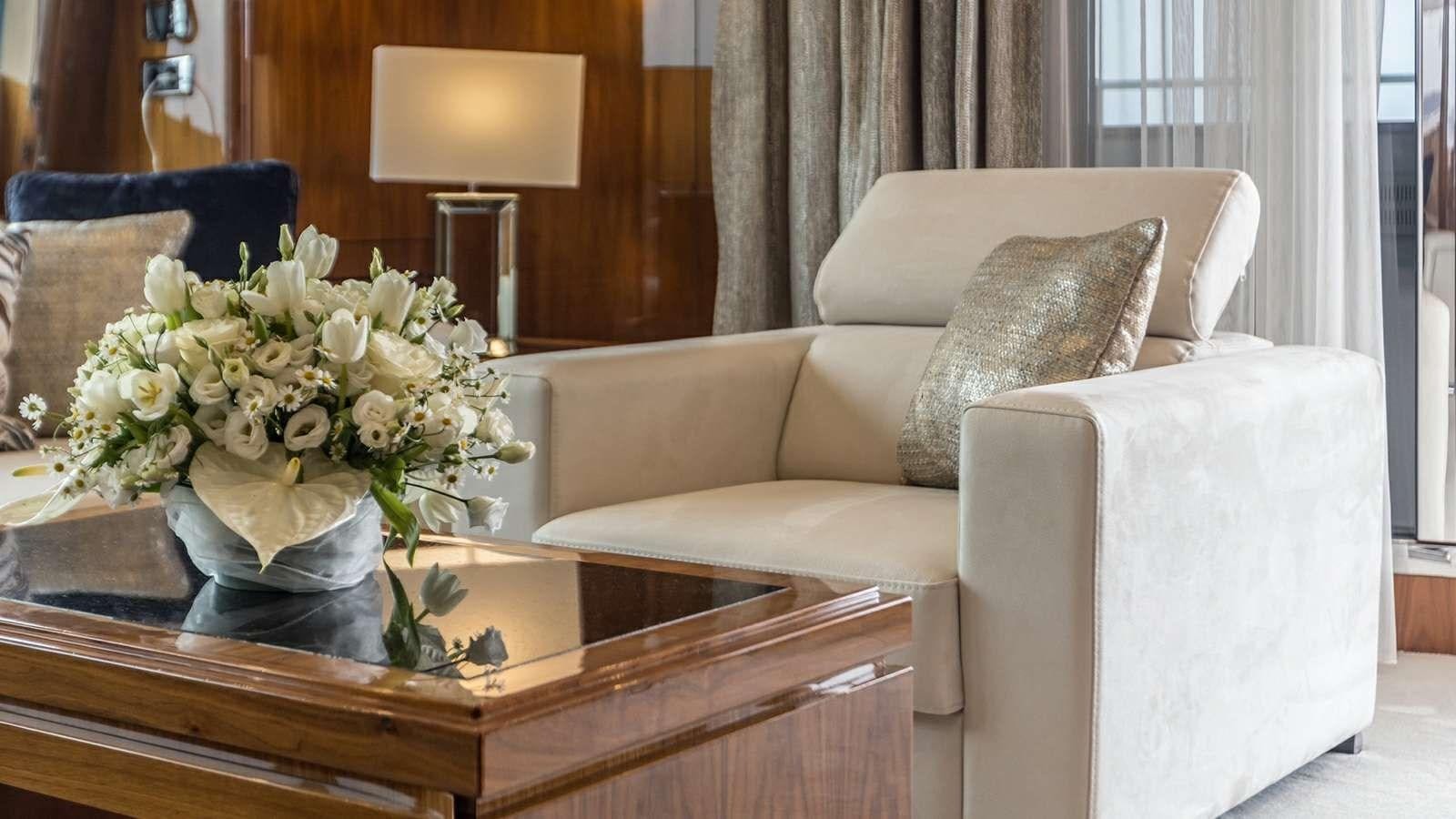 a living room with a white couch and a table with flowers aboard KATARIINA I Yacht for Sale
