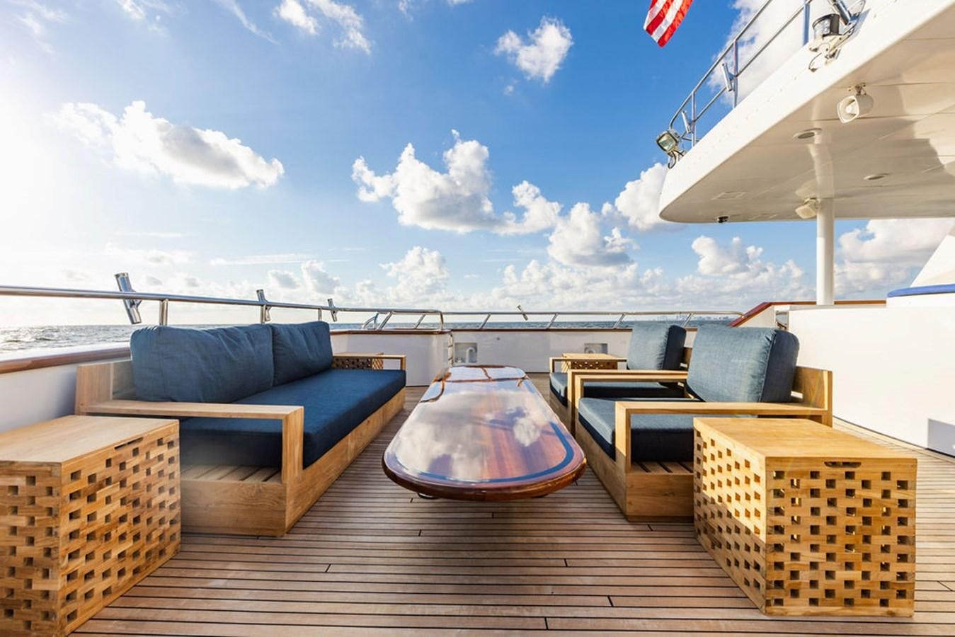 a deck with chairs and a table on it aboard EMPIRE SEA Yacht for Sale