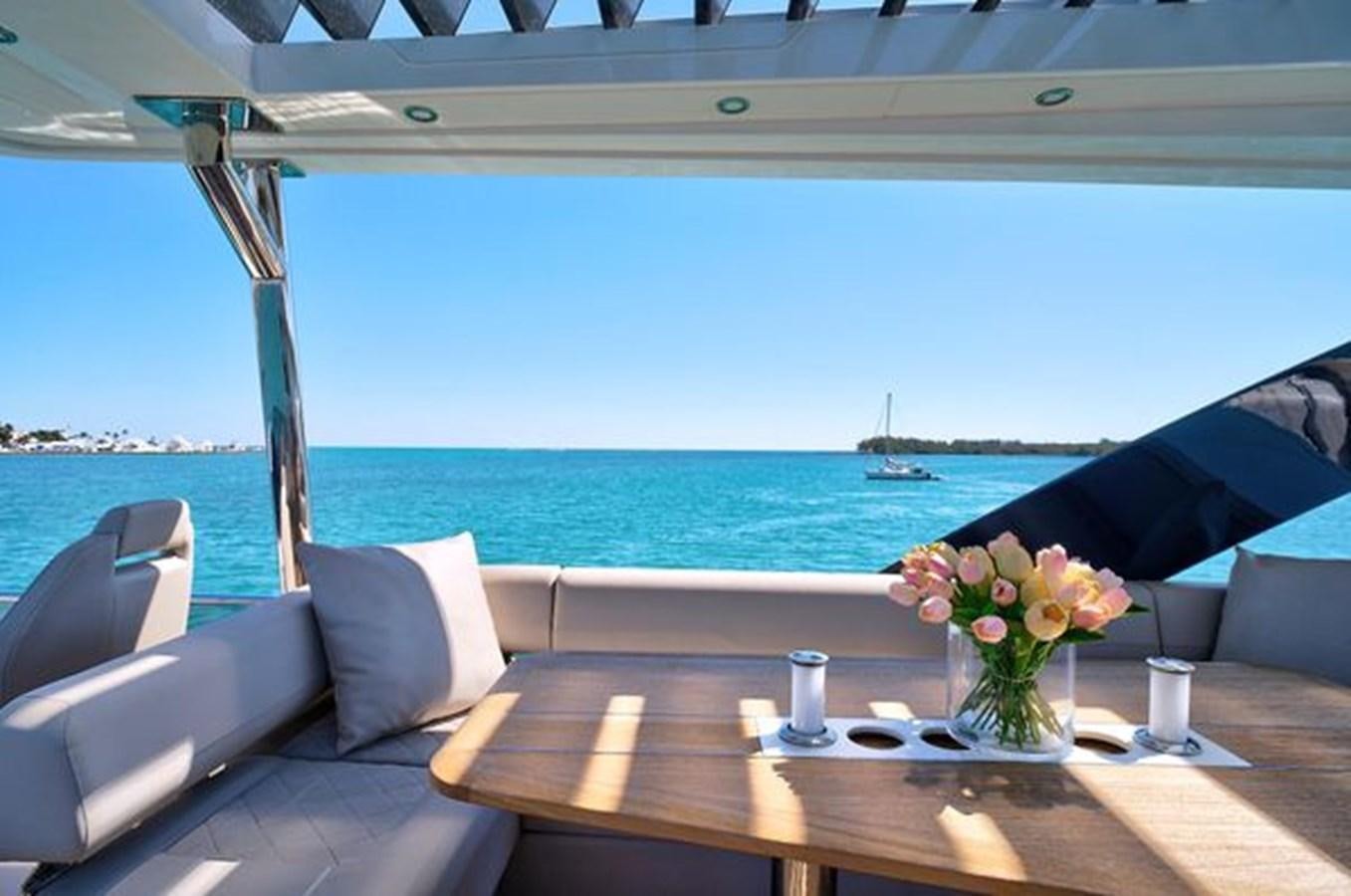 a table with chairs and a view of the ocean aboard 2021 FAIRLINE SQUADRON 68 Yacht for Sale