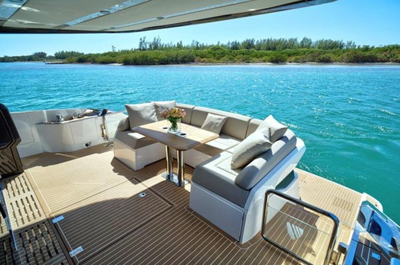 a deck with chairs and a table on it by a body of water aboard 2021 FAIRLINE SQUADRON 68 Yacht for Sale