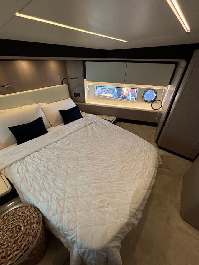 a bed with a white comforter and a television above it aboard ATLANTIS OF LONDON Yacht for Sale
