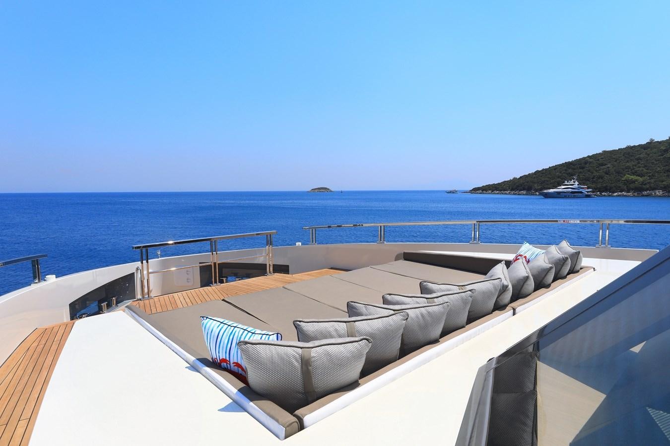 a lounge chair on a deck overlooking a body of water aboard TORTURA Yacht for Sale