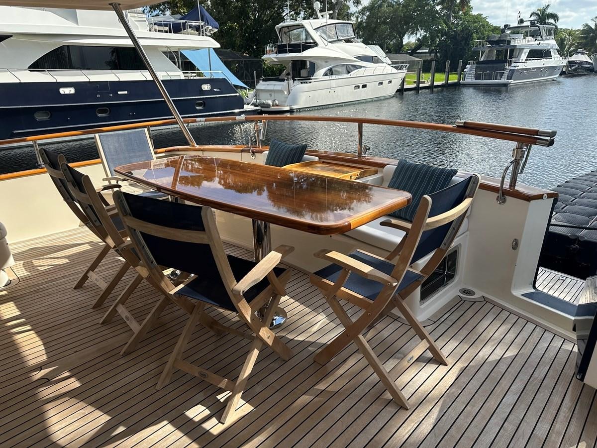 a wooden table on a deck overlooking a marina with boats aboard BANDOL Yacht for Sale
