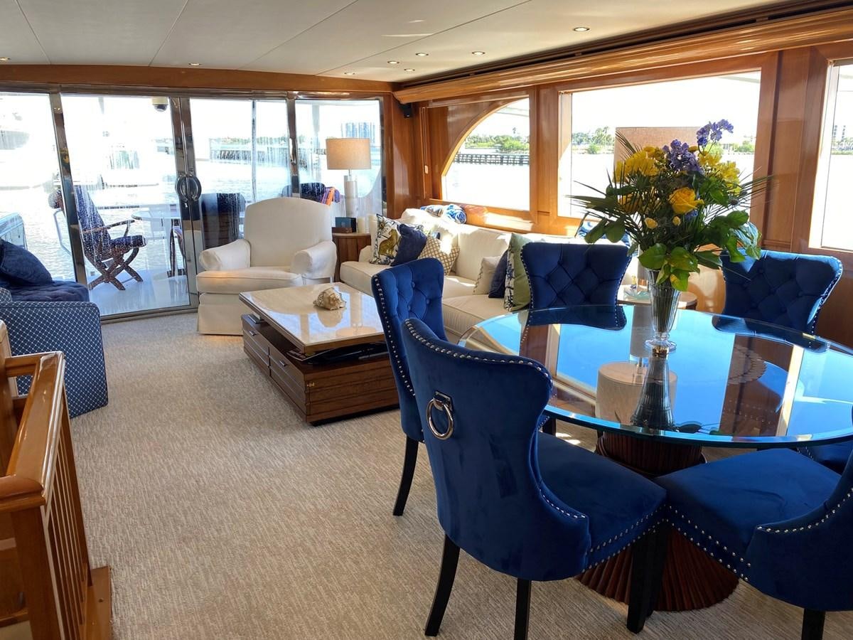 a living room with blue chairs and a table with flowers in it aboard DREAM ON Yacht for Sale