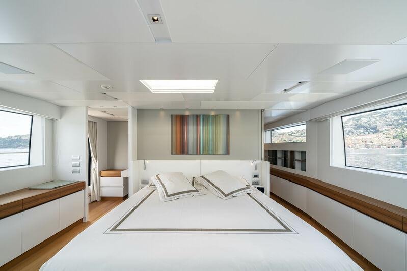 a large white room with a large bed and a desk aboard SALT Yacht for Charter
