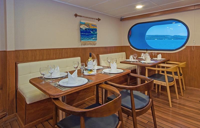 a dining table with chairs and a window aboard TIP TOP II Yacht for Charter