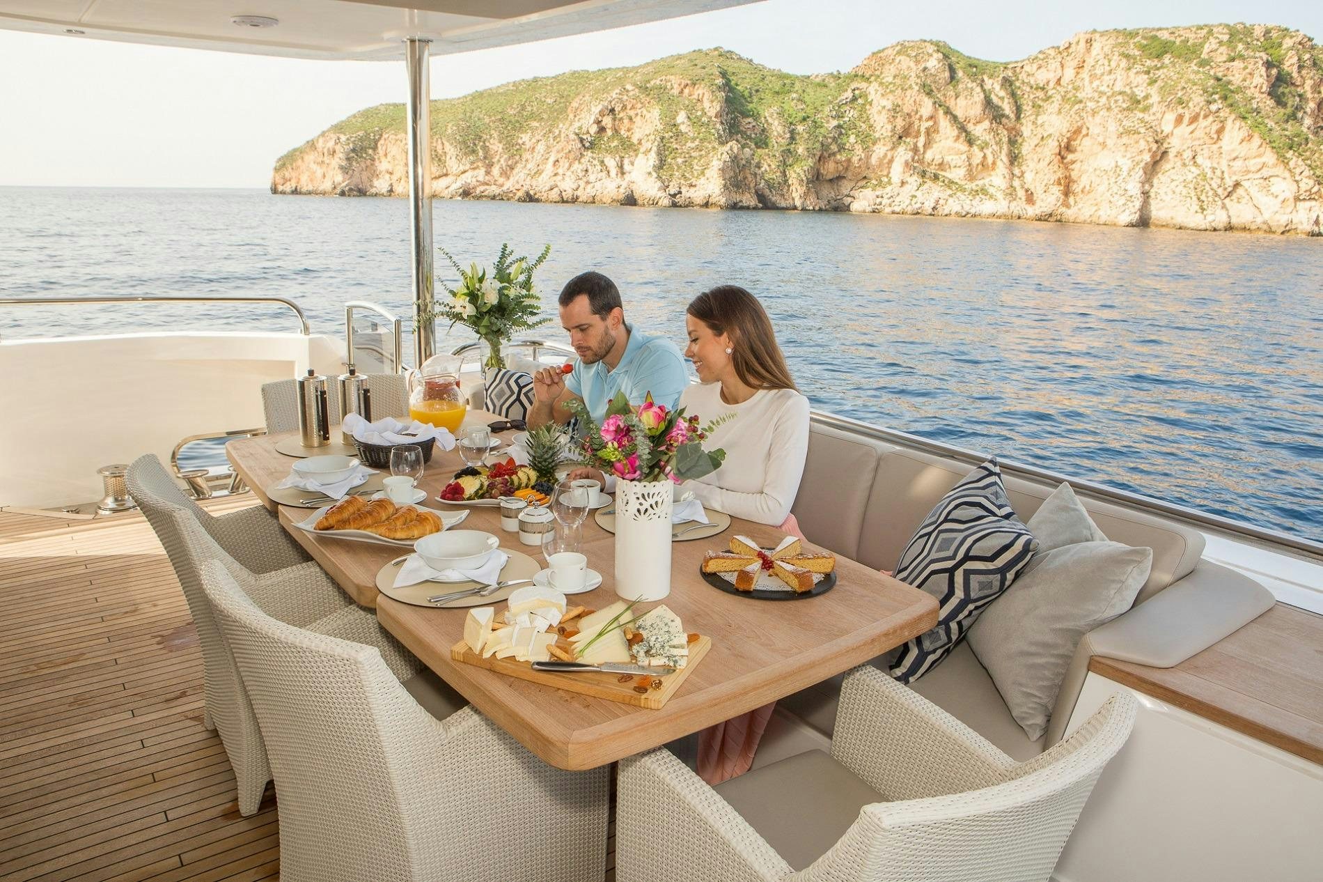 a couple sitting at a table with food on it aboard KOHUBA Yacht for Charter