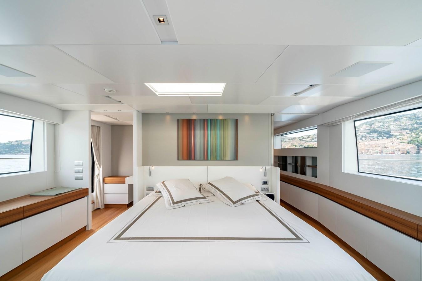 a large white bedroom with a large window and a desk aboard SALT Yacht for Charter